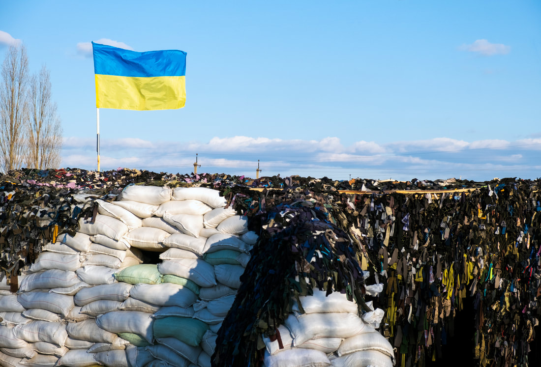 Ukrainian flag blue yellow color flutters in blue sky on barricades